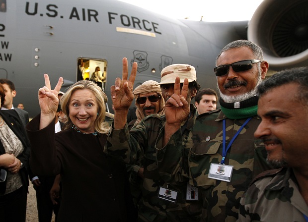 U.S. Secretary of State Hillary Clinton (C) gestures with Libyan soldiers upon her departure from Tripoli in Libya October 18, 2011.  REUTERS/Kevin Lamarque  (LIBYA - Tags: POLITICS TPX IMAGES OF THE DAY MILITARY) - RTR2ST1X